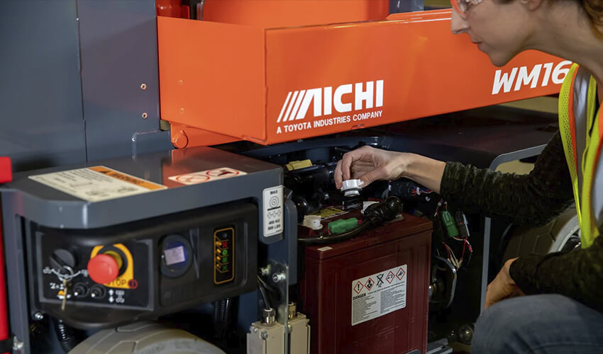 A Liftow service technician performing maintenance on a forklift battery